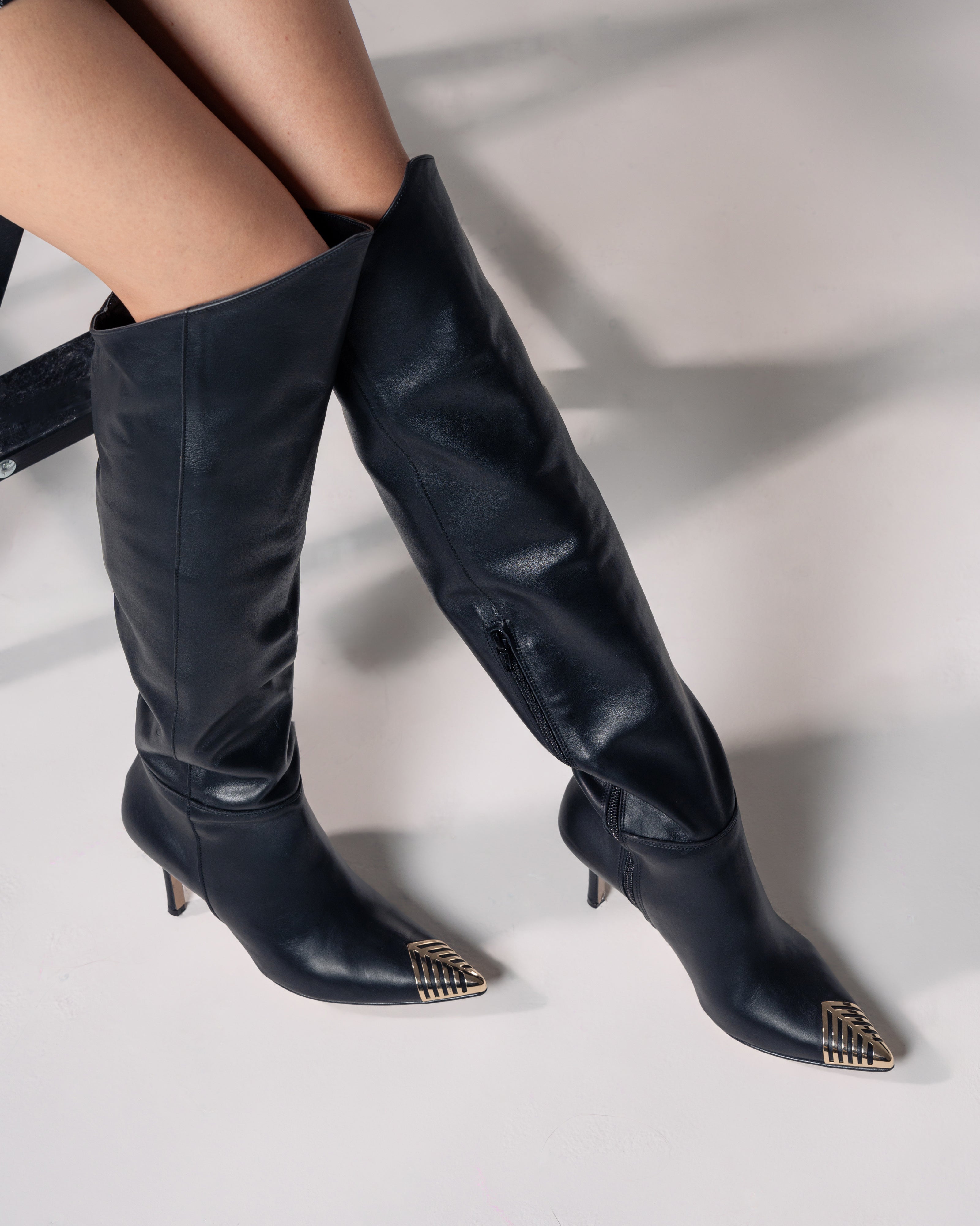 OBLIQUE - Tubular boot in genuine leather with asymmetric cut and gold plaque